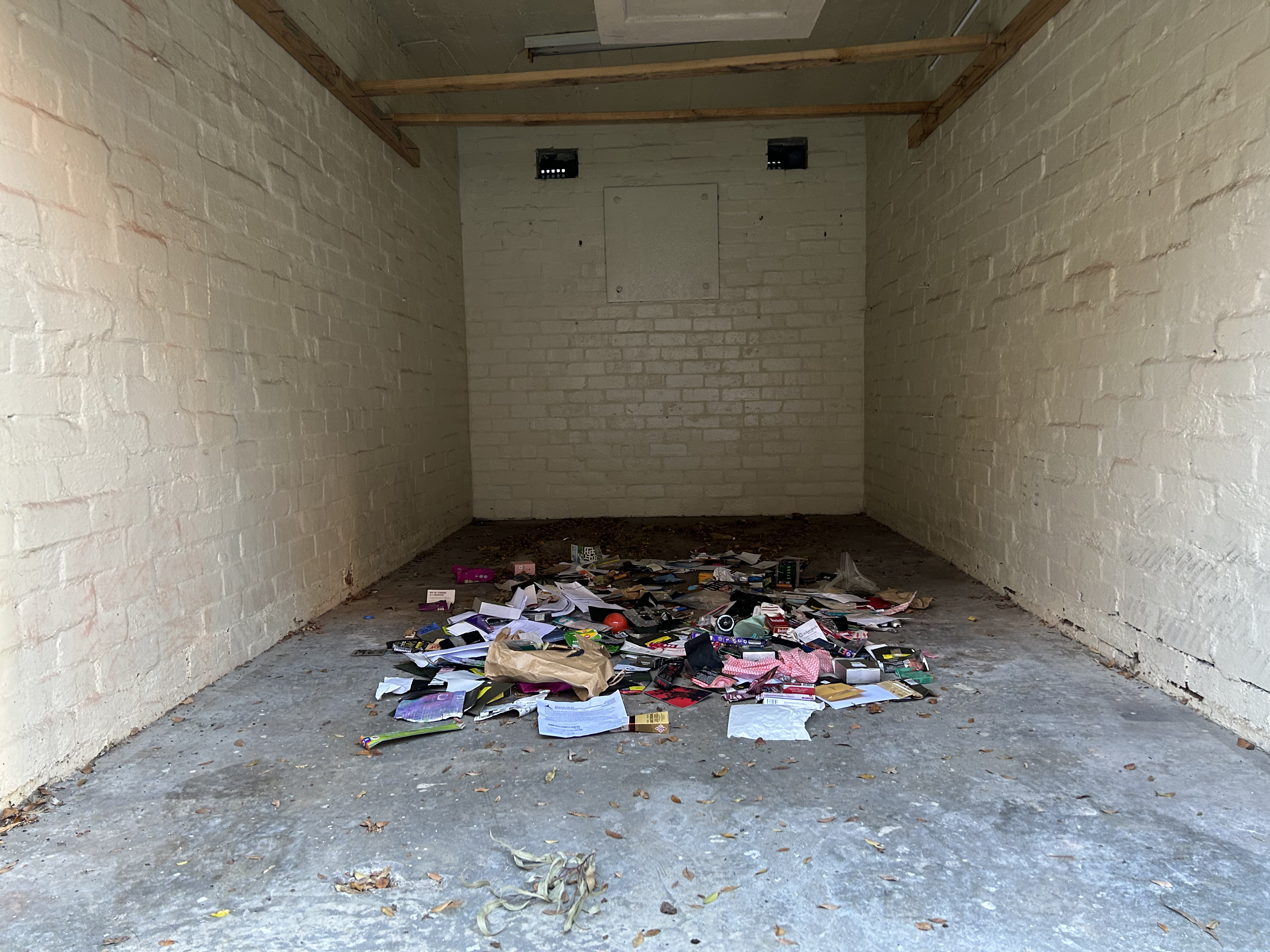installation view, front on, colourful trash on a garage floor. front angle