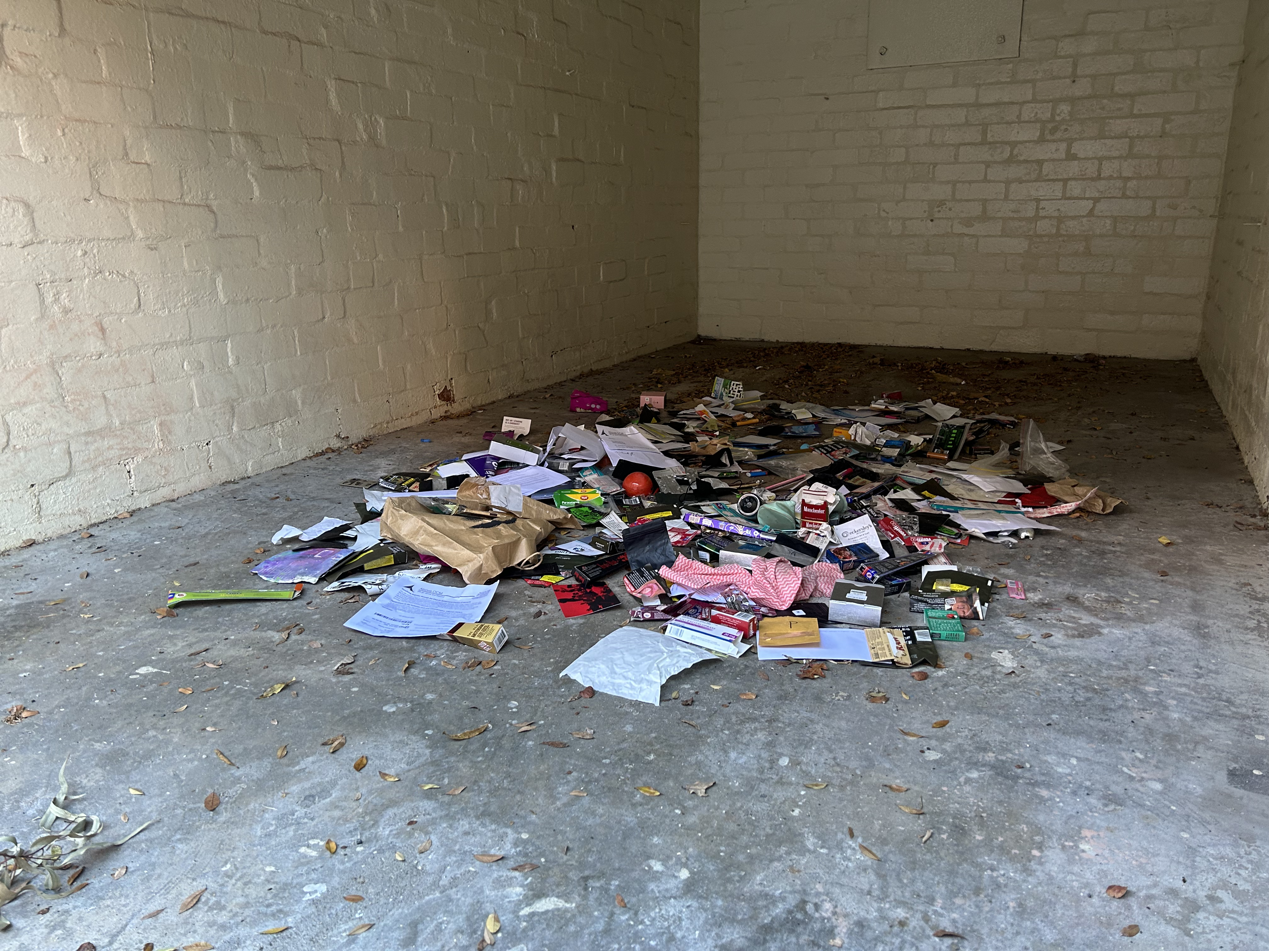 installation view, front on, colourful trash on a garage floor. left diagonal