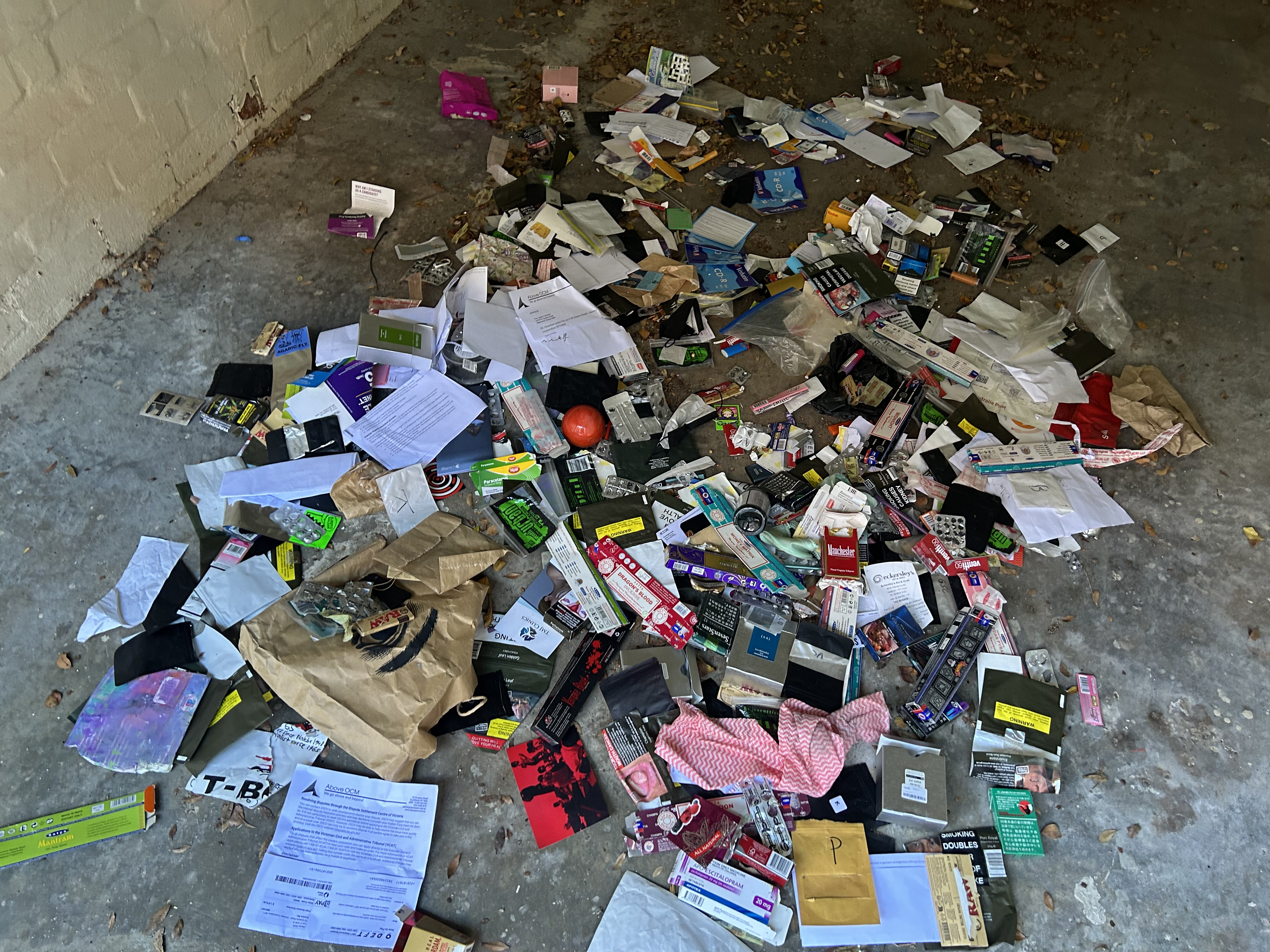 installation view, front on, colourful trash on a garage floor. close up